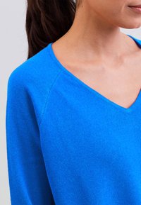 Blauer leichter Pullover mit V-Ausschnitt, langen Ärmeln und einer weichen Strickstruktur. Verfügt über ein glattes Finish und dezente Nähdetails.