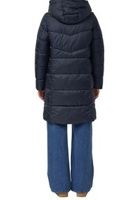Manteau matelassé marine avec capuche, présentant des sections horizontales matelassées et une coupe plus longue, associé à un pantalon en denim à jambes larges. Texture lisse.