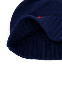 Căciulă de tricot de marină cu manșetă îndoită ribbată. Fabricată dintr-un material moale, cu un detaliu mic de logo roșu pe lateral. Textură netedă în general.