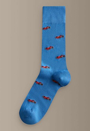 Modrá ponožka s malými červenými vzormi pretekárskych áut rovnomerne rozmiestnenými po celom tkanine, zobrazená na neutrálnom pozadí.