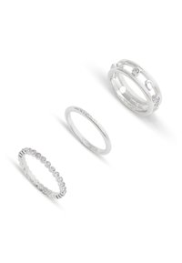 Tres anillos de plata: una banda lisa, un anillo delgado con piedras igualmente espaciadas, y un diseño con recortes y piedras engastadas.