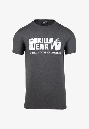 Pelēka kokvilnas T-kreklis ar īsām piedurknēm. Uz tā ir balts teksts "GORILLA WEAR" un "UNITED STATES OF AMERICA" ar gorilas grafiku.