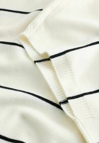 Tissu tricoté blanc avec des rayures horizontales noires. Présente une texture lisse et des bords côtelés, mettant en valeur un design doux et confortable.