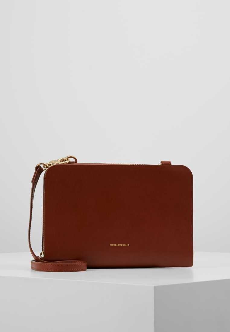 Braune Leder-Umhängetasche mit minimalistischem rechteckigem Design, goldfarbenem Logo, dünnem Schulterriemen und Reißverschluss.