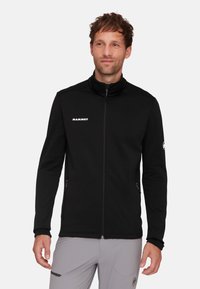 Schwarze Fleecejacke mit Reißverschluss, hohem Kragen und zwei Seitentaschen. Verfügt über ein weißes Logo und ein einfaches, schlankes Design. Glatte Textur.