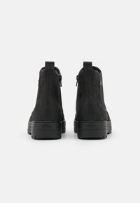 Bottes à cheville noires en daim avec une finition lisse. Dotées d'une fermeture éclair à l'arrière et d'une semelle texturée. Logo de la marque visible sur le talon.