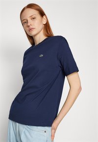 Navy blue crew-neck t-shirt made of soft cotton. Features short sleeves and a small green crocodile logo on the left chest.