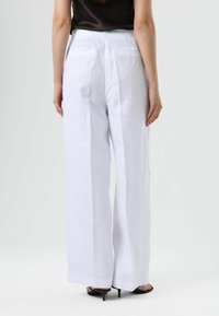 White linen wide-leg pants with a smooth texture, featuring two back pockets and a tailored fit. Hem finishes are clean and sharp.