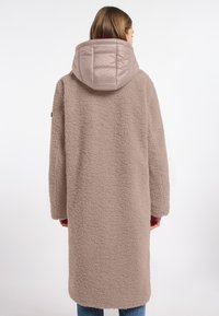 Beige oversized jas met een gestructureerde, fleece-achtige buitenkant en een lichtbeige, gewatteerde capuchon. Heeft lange mouwen en een rechte zoom.