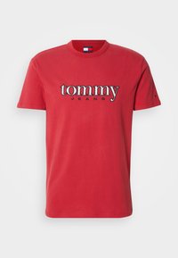 Camiseta de algodón roja con cuello redondo, mangas cortas y un logo bordado en contraste "tommy JEANS" en el pecho.