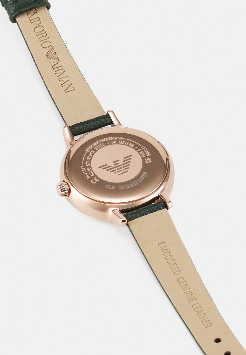 Zegarek ze stali nierdzewnej w kolorze różowego złota z zielonym, tłoczonym paskiem ze skóry naturalnej. Posiada gładkie tylne wieko z grawerem marki oraz informację o wodoodporności.