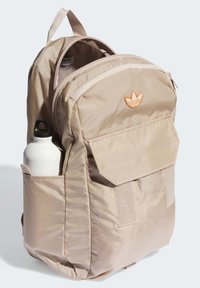 Beige fabric backpack with a zippered main compartment and front pocket, featuring an embroidered logo and side pocket for a water bottle.