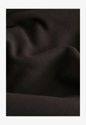 Primo piano di un morbido tessuto marrone scuro con una fine trama e delicati pieghe che creano ombre e luci.