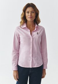 Camicia button-up rosa chiaro con maniche lunghe, caratterizzata da un piccolo ricamo di un orsetto sul petto, realizzata in un tessuto morbido.