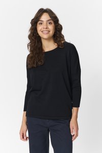 Sort strikket sweater med lange ærmer, rund halsudskæring og en struktureret overflade. Sammen med mørkeblå bukser.