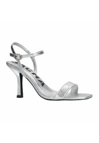 Zilveren hoge hakken sandalen met een metallic afwerking, voorzien van dunne enkelriemen en een vierkante teen. Een decoratieve gesp is aanwezig op de riem.