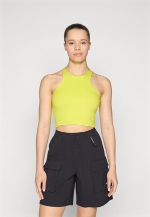 Lys limegrønn avkortet tanktop med høy hals, parret med svarte cargo-shorts med sidelommer og elastisk midje.