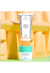Beste No. 9 Jelly Cleanser in a white tube with black patterns, and Protini Polypeptide Cream in a turquoise jar, both against a yellow backdrop.