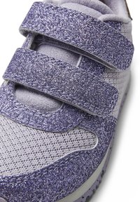 Scarpa sportiva glitter viola con cinturini in velcro, tessuto in rete e suola grigia testurizzata di forma arrotondata e accenti vivaci.