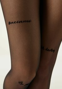 Schwarze, transparente Strumpfhosen mit glatter Textur, versehen mit Schriftzügen: "Baciami" und "Oh darling," auf den unteren Beinbereichen.