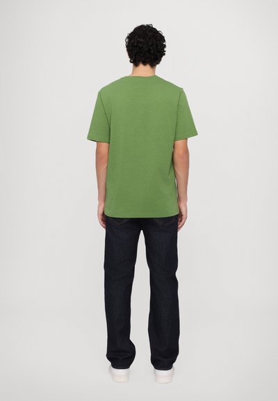 Short-sleeve green t-shirt with a crew neckline, paired with dark blue jeans. The fabric appears smooth with a relaxed fit.