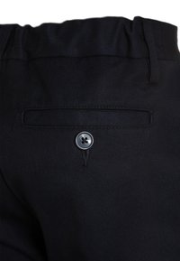 Pantalons noirs en tissu texturé, dotés d'une poche arrière et d'un détail en bouton argenté. La taille présente un design froncé pour plus de confort.