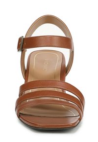 Brown strappy sandal with a block heel, featuring a smooth leather finish, adjustable ankle strap, and open toe design. Brand name visible inside.