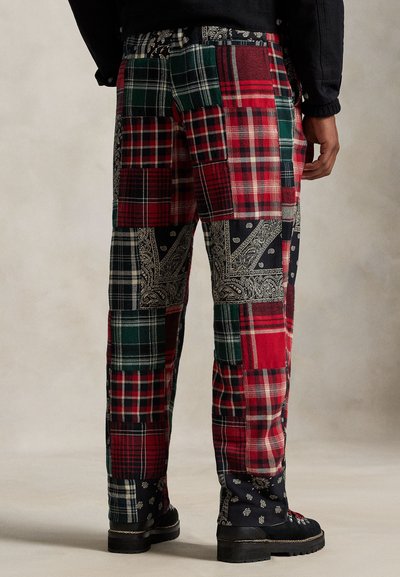 Spodnie patchworkowe z różnymi wzorami w kratę i paisley w kolorach czerwonym, zielonym i czarnym. Tkanina ma teksturowany wygląd i liczne kieszenie.