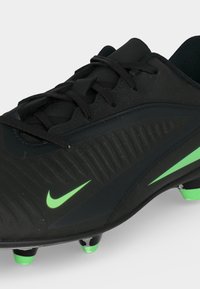 Μαύρο παπούτσι ποδοσφαίρου Nike με πράσινες λεπτομέρειες και αγκάθια, με υφή στις πλευρές και μαύρα κορδόνια σε λευκό φόντο.
