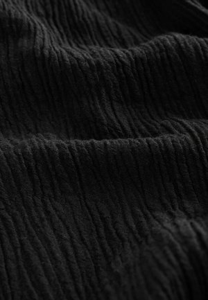 Tissu noir froissé avec une surface texturée, présentant de profonds reliefs et des nuances variées, créant une apparence dimensionnelle.