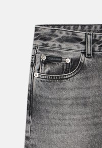 Svarta jeans i denim med en subtil acid-wash-effekt, en framficka med en svart Calvin Klein-etikett och silverfärgade detaljer.
