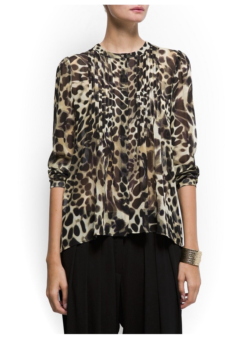 Blouse en satin avec un imprimé animal crème et marron, détails plissés à l'avant et manches trois-quarts, associée à un pantalon noir.