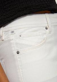 Valkoiset farkut, joissa on kapea istuvuus, jäljittelee koristepocketia, kaksi etutaskua, hopeista metalliosaa ja pieni "QS"-label vyötäröllä.