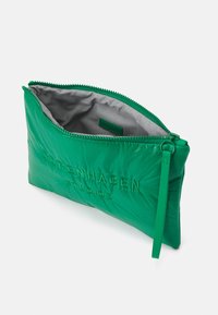 Pochette en nylon vert avec une finition texturée, dotée d'une fermeture éclair et du logo en relief "Copenhagen Studios" à l'avant. Doublure intérieure grise.