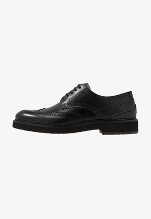 Chaussure brogue en cuir noir avec des détails perforés ; design à lacets, bout arrondi et semelle en caoutchouc pour la durabilité. Texture lisse avec finition polie.
