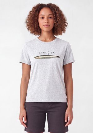 Femme aux cheveux bouclés portant un t-shirt gris clair avec une illustration réaliste d'une sardine et le texte "Niedliche Sardelle".