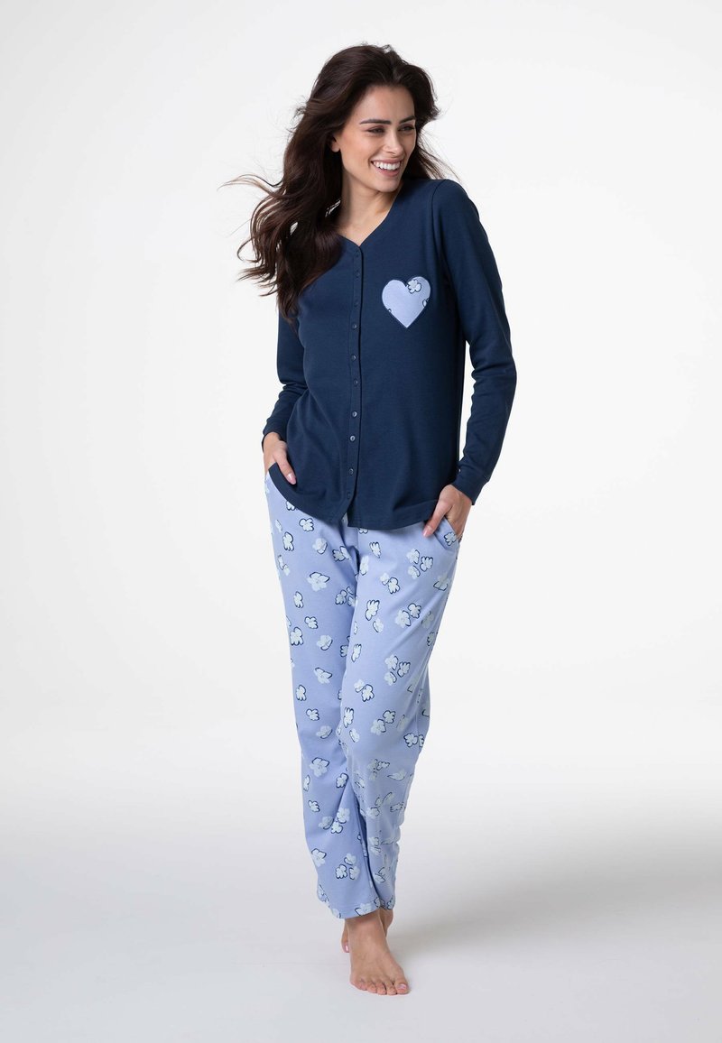 Maglietta blu navy a maniche lunghe con bottoni e una toppa a forma di cuore; pantaloni del pigiama azzurri chiaro con motivo a nuvole. Tessuto morbido con vestibilità comoda.