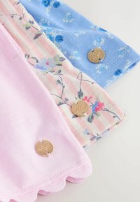 Tre pezzi di tessuto piegati nei motivi rosa, floreale a righe rosa e floreale blu, ciascuno con un piccolo bottone decorativo rotondo dorato.