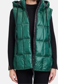 Zelená prošívaná zateplená vesta s kapucí, předním zipem a bočními kapsami. Vyznačuje se lesklou, hladkou texturou a kontrastním černým podšímáním.