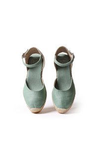 Žalios audinio espadrilės su kulkšnies dirželiais, natūralios jūtos padais ir lygiu paviršiumi. Suapvalinta noselė ir minimalistiškas dizainas.