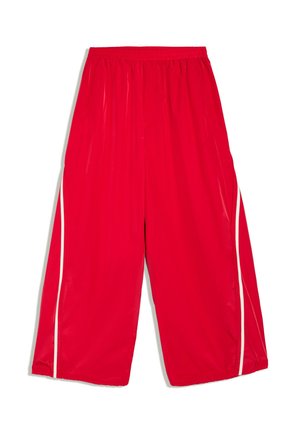 Pantalon ample rouge vif avec une ceinture élastique et des rayures blanches verticales le long des côtés extérieurs de chaque jambe.