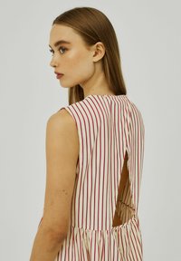 Abito senza maniche con strisce verticali rosse e bianche, vita arricciata e apertura a chiave sul retro con chiusura a bottone.