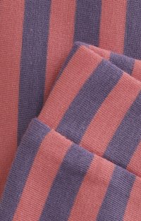 Nahaufnahme von gefaltetem Strickstoff mit breiten vertikalen Streifen in Pink- und Violetttönen.
