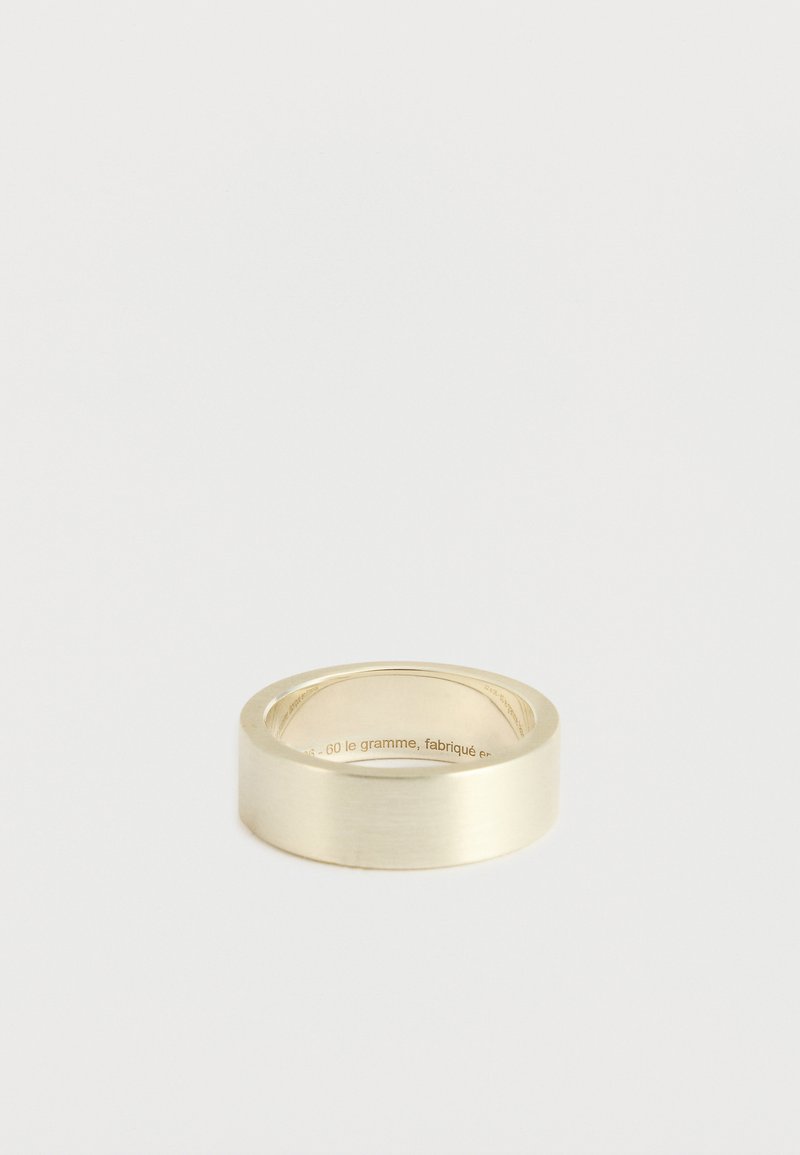 Guldtonet metalring med en glat, børstet overflade. Flad design, afrundede kanter, med indgraveret tekst på den indre del af ringen.