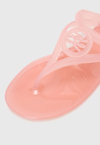 Rosa gelésandal med en glänsande yta, T-formad rem och cirkulär logotypdetalj. Har en platt sula och genomskinligt material.