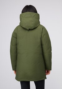 Giacca insulator verde oliva con cappuccio, caratterizzata da un motivo trapuntato nella parte superiore, tasche laterali con zip e taglio dritto.