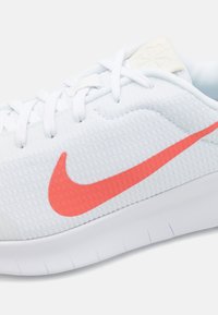 Nike atletska cipela s gornjim dijelom od svijetloplavog mrežastog materijala, koja ima istaknuti koraljni swoosh, bijele vezice i teksturiranu đon.