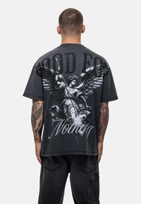 Czarny bawełniany t-shirt z dużą grafiką anioła z skrzydłami i włócznią z tyłu, z napisem "DOBRY NA NIC."