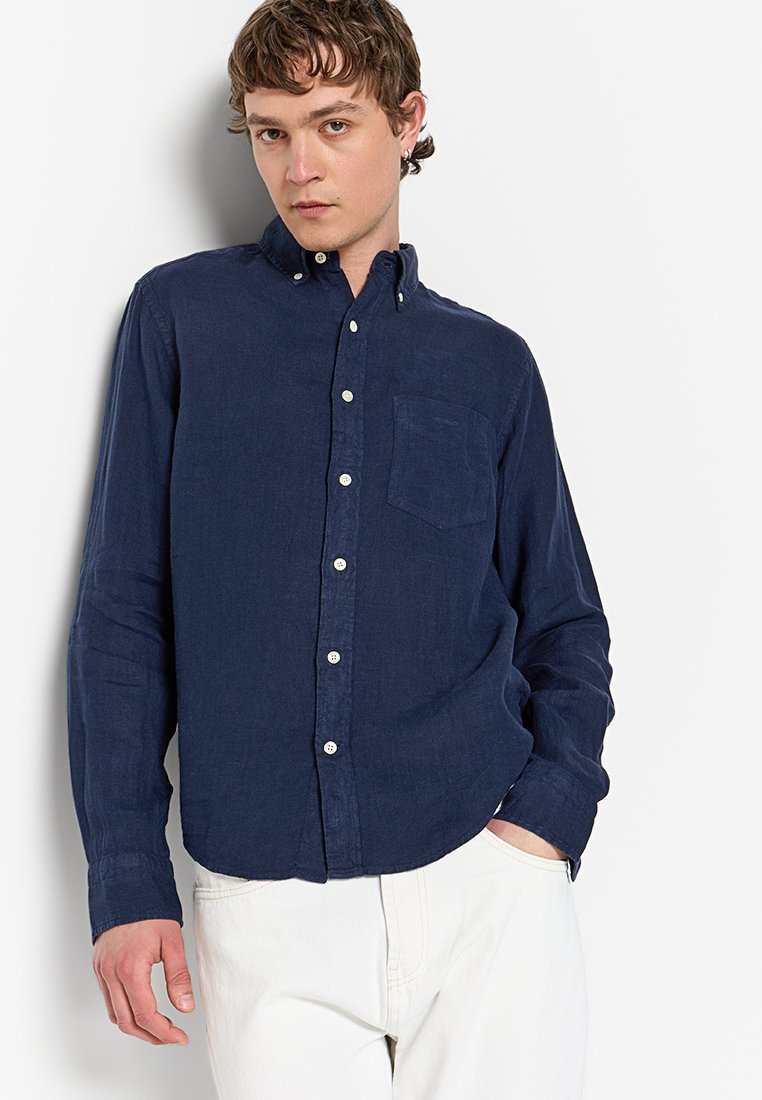 Camisa de algodón de manga larga en color azul marino con cuello abotonado, bolsillo delantero y botones blancos. Textura suave, corte relajado.