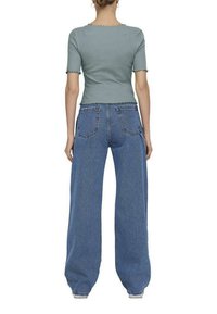 Haut à rayures bleu clair à manches courtes et bords festonnés, associé à un jean en denim bleu taille haute, ample, avec poches arrière.